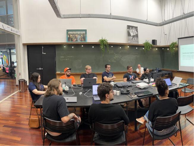 Indoor photo of ten Able team members sitting at a conference table focused on a slide